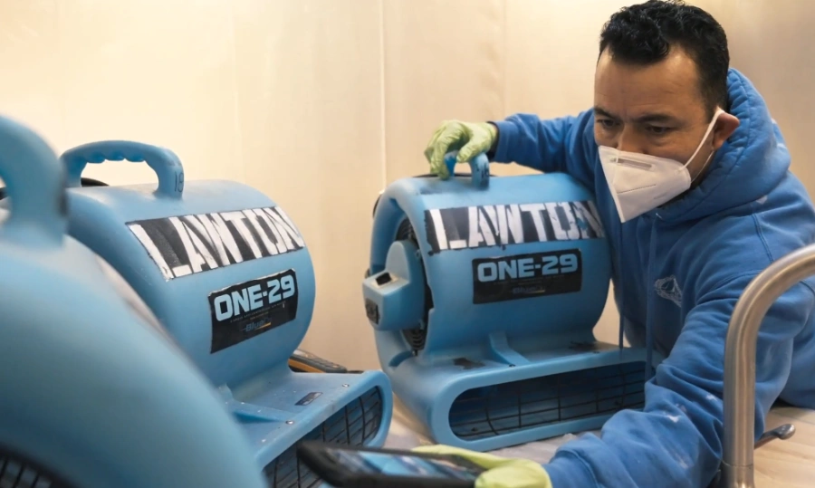 IICRC-certified water damage restoration technician setting up commercial air movers for structural drying in a Bellevue, WA home